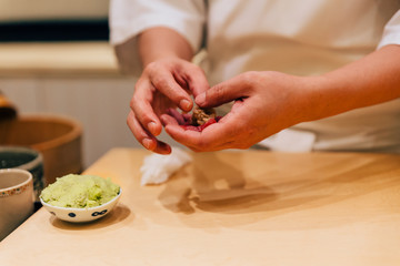Japanese Omakase Chef making Chutoro Sushi (Medium Fatty Bluefin Tuna), pasting fresh wasabi neatly by hands. Japanese traditional and luxury meal.