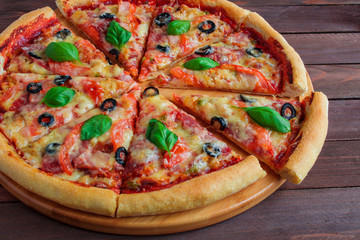 delicious homemade sliced pizza with tomatoes cheese basil olives on wooden background 