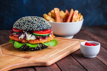 healthy burger with black bun carrot patty vegetables fries potato sauce bowl