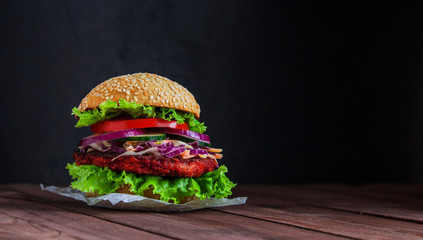 healthy veggie burger with beet patty coleslaw salad cucumber tomatoe lettuce on dark wooden...