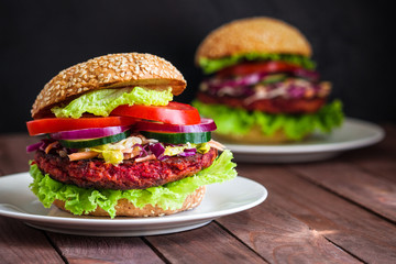 healthy vegan burgers with beet patty coleslaw salad cucumber tomatoe lettuce on plate on dark wooden background 