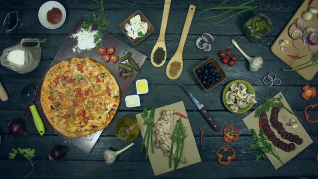 Cheeseburger pizza on ecological black background.  Big pizza is on eco black table. Pizza consists of ingredients: cucumbers, spices, tomatoes, meat, chicken, sauce, cheese.