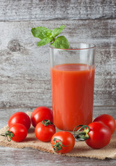 Close-up of a glass of tomato juice with vegetables on wooden sacking background. Vitamins and minerals. Healthy drink concept.