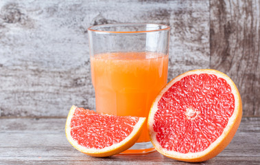 A glass of ripe grapefruit with juice on wooden table close-up