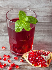 A glass of pomegranate juice with fresh pomegranate fruits on wooden table. Vitamins and minerals. Healthy drink concept.