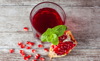 A glass of pomegranate juice with fresh pomegranate fruits on wooden table. Vitamins and minerals. Healthy drink concept.
