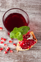A glass of pomegranate juice with fresh pomegranate fruits on wooden table. Vitamins and minerals. Healthy drink concept.