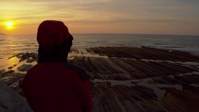 Hiker contemplate sunset from cliff