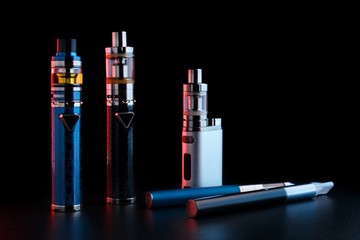 electronic cigarettes or vaping devices on black background. Toned light