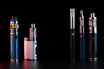electronic cigarettes or vaping devices on black background. Toned light