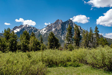 Wild mountains of Idaho with snow on them and blue sky with shite cotton ball clouds