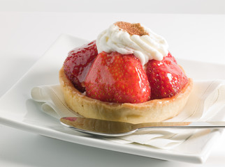 Tarta de fresas con nata con cuchara sobre fondo blanco, postre. Strawberry cake with cream with spoon on white background, dessert.