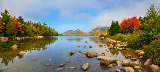 View of the clear water, stones and fall foliage of Jordan Pond in Acadia National Park