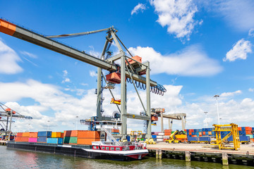 Container ship and logistics. Crane loading a container ship at Rotterdam port - obrazy, fototapety, plakaty
