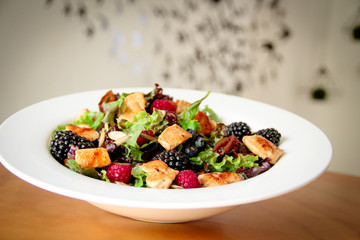 Healthy salad bowl with grilled chicken, caramelized onion and berries.