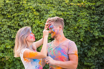 Friendship, festival of holi, people concept - young couple playing with colors at the festival of holi