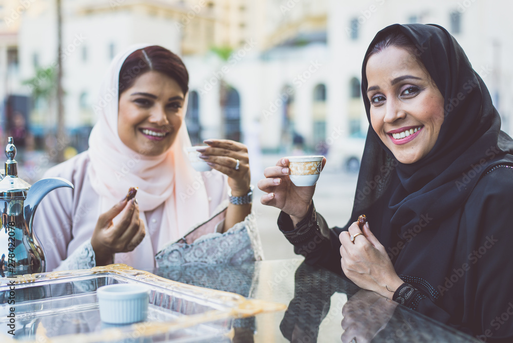 Wall mural Two arabian girls spending time togehter outdoor making activities