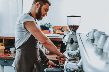 Concentrated barista using tamper and looking serious