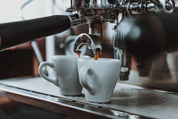 Close up of fresh coffee pouring into two cups