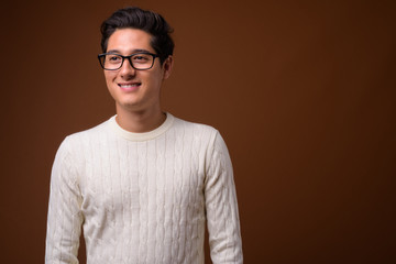 Obraz premium Young multi-ethnic handsome man against brown background