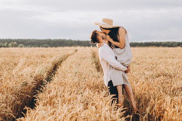 Naklejka na ściany i meble Young couple in love outdoor.Stunning sensual outdoor portrait of young stylish fashion couple posing in summer Wheat Field. selective focus