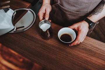 Close up of pitcher with milk and cup of coffee
