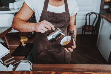 Close up of barista pouring milk from the pitcher