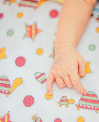 hand of a sleeping newborn baby lying on a baby blanket
