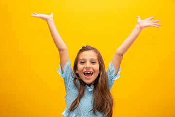 Very happy child celebrating on yellow background. Winner, birthday and gift concept.