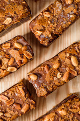Chocolate brownie with nuts on a black plate on a yellow set on a wooden table in a restaurant. Cappuccino on the background. Close up. Space