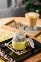 yellow chia pudding in a jar on a wooden table in the restaurant. Beautiful chia pudding serving in a restaurant on a yellow background. close up