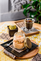 Coffee and traditional Italian dessert tiramisu in a jar on a wooden table in the restaurant. Beautiful pumpkin tiramisu serving in a restaurant on a yellow background. close up