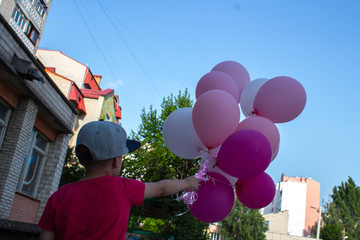 boy holds in his hand a lot of colored balloons