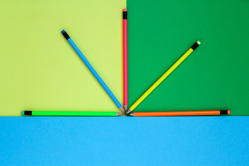 five pencils neon colors lie on a coloured background like a fan. copy space.