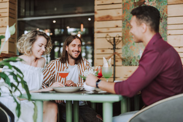 Three friends chatting and laughing in cozy cafe