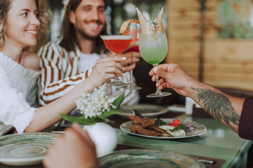 Three friends toasting with cocktails while spending time in cafe