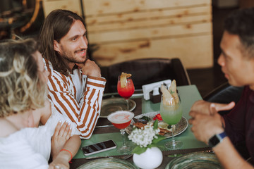 Three friends chatting and enjoying cocktails in cafe