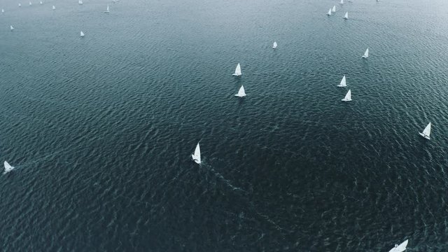 Training sailing yachts float on the sea. Yachting and sailing training. Aerial view top slide turn drone of the blue sea and small training sailing yachts with athletes in the regatta