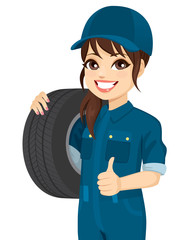 Female mechanic holding tire wheel making positive thumb up