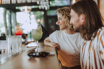 Beautiful couple sitting at the bar counter with cocktails