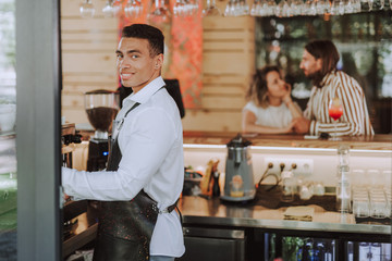 Handsome bartender in black apron working in cafe