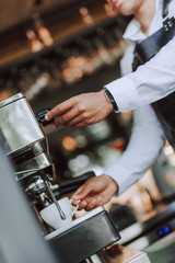 Barista using professional coffee machine to make fresh espresso