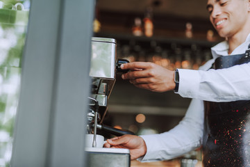 Handsome barista using professional coffee machine to make fresh espresso