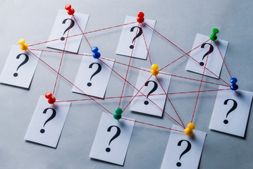 Network of printed question marks on white cards