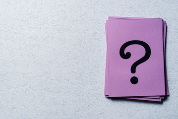 Stack of question marks on purple paper