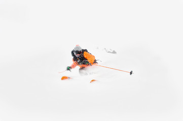 Professional Skier athlete rides out of deep snow while performing a skiing trick in a snowstorm. The winter season is a good powder day. Winter extreme sports