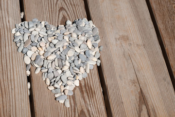 heart of sea pebbles on wood texture