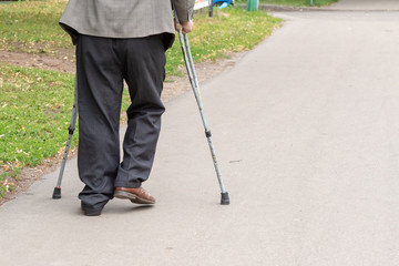 an elderly man walking on crutches on the street