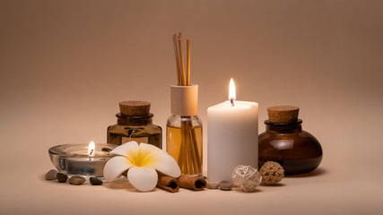 Beautiful spa composition with candles, frangipani flower, oil flasks and other decor elements.