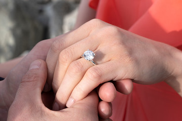 Closeup of man's hand holding a woman's hand with diamond ring